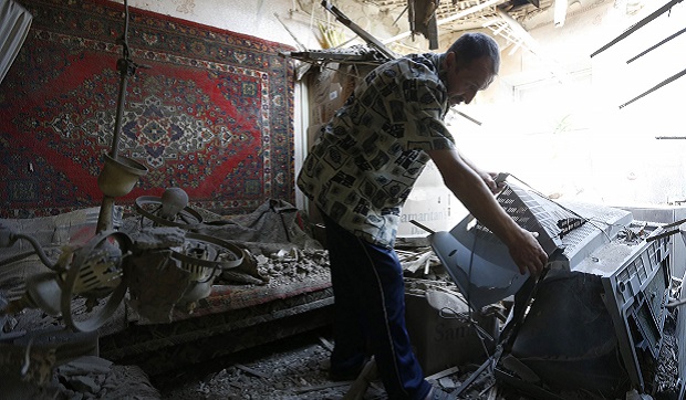 A man searches through the debris of his house, ruined during recent shelling in Donetsk